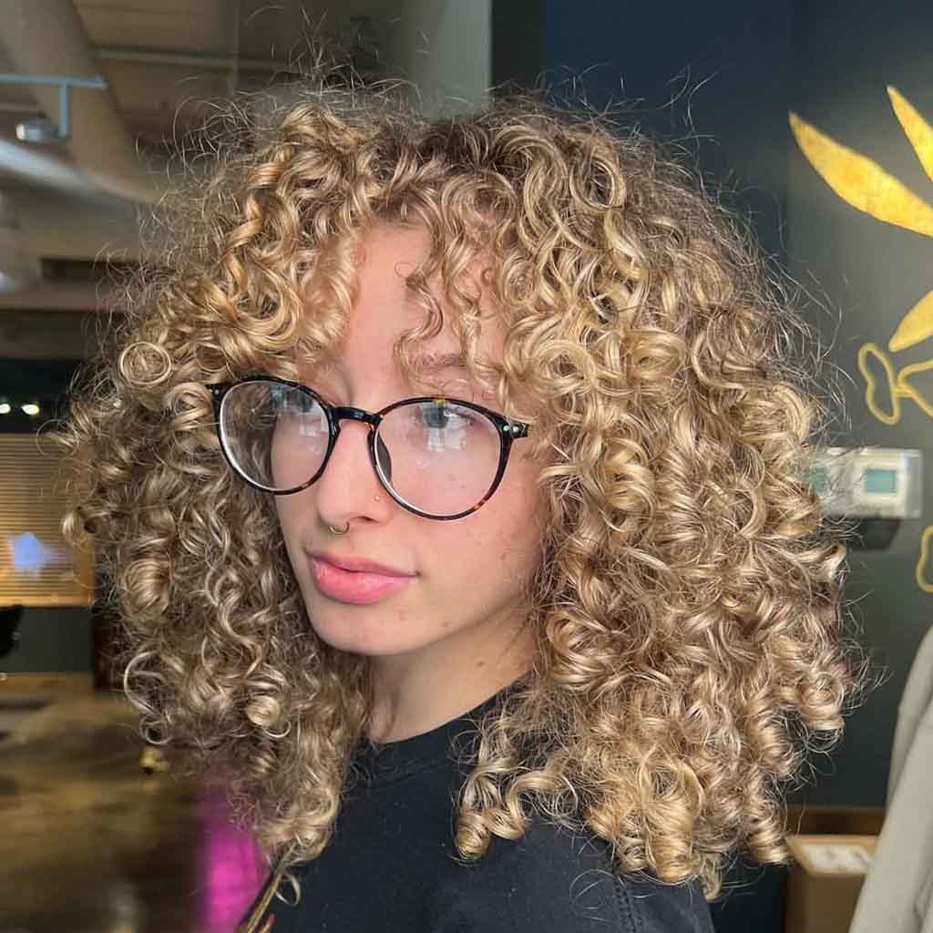 Golden Bouncy Curly Shag With Blonde Balayage and Curly Bangs